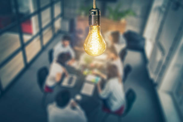Light bulb shining above a group of researchers sitting at a table 